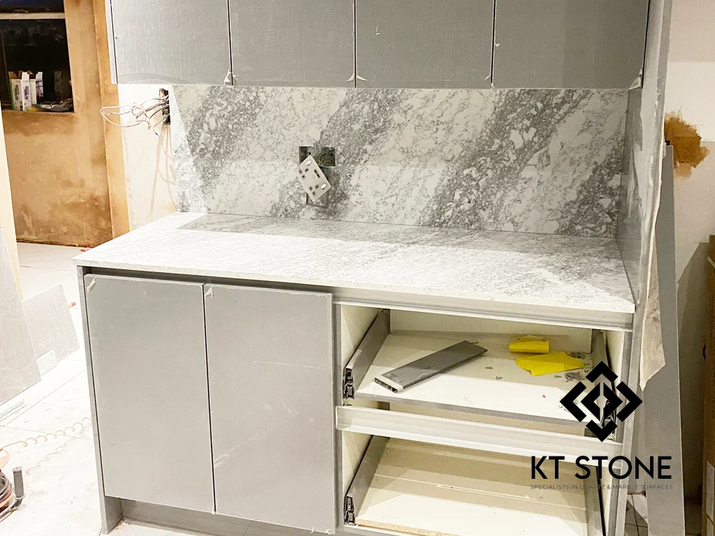 Grey veined stone worktops with a matching splashback, from a KT Stone project in London.