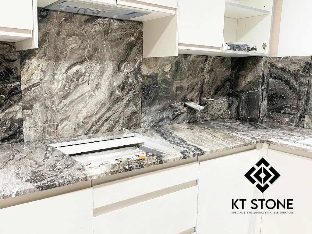 Grey veined stone splashback and worktop behind a hob, from a KT Stone project in London.